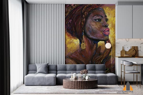Vibrant portrait of an African woman as a large wall mural in a modern living room with a grey sofa.