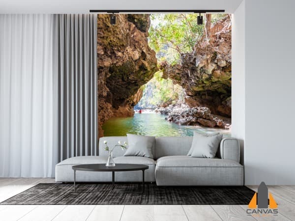 Cave opening overlooking a water passage wall mural in a modern living room with a grey sofa.
