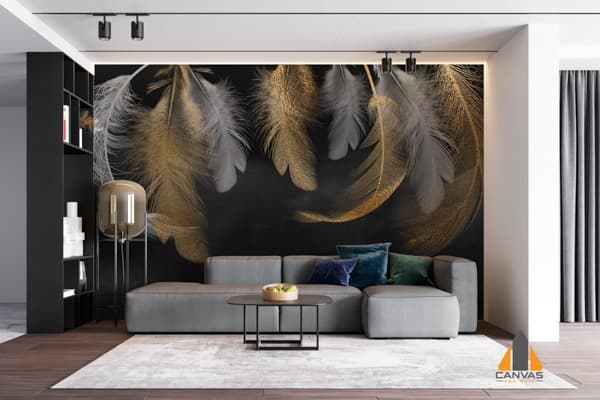 Gold and white feather wall mural in a modern living room with a grey couch and black shelves.