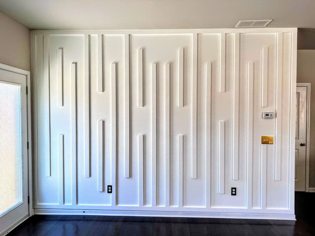 White accent wall with geometric wood panels, a modern custom wallpaper installation.