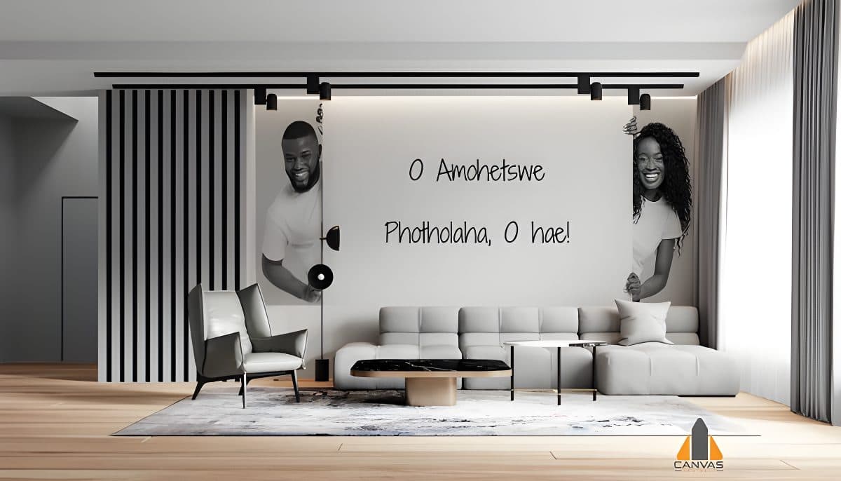 Smiling Black man and woman peeking playfully from behind a custom wallpaper installation of Setswana text.