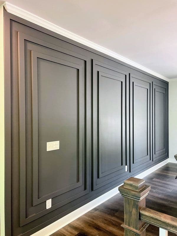 Dark gray accent wall with raised panels in a modern home, perfect for custom wallpaper installations.