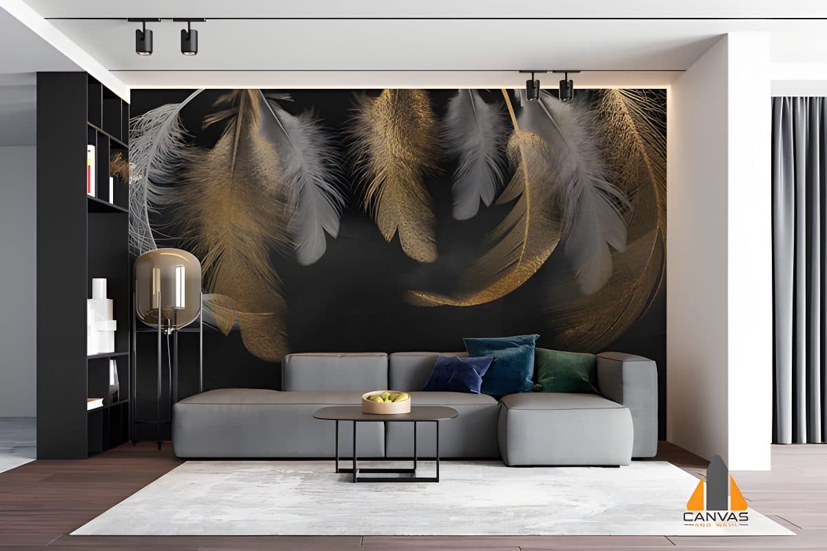 Gold and white feather wall mural in a modern living room with a grey couch and black shelves.