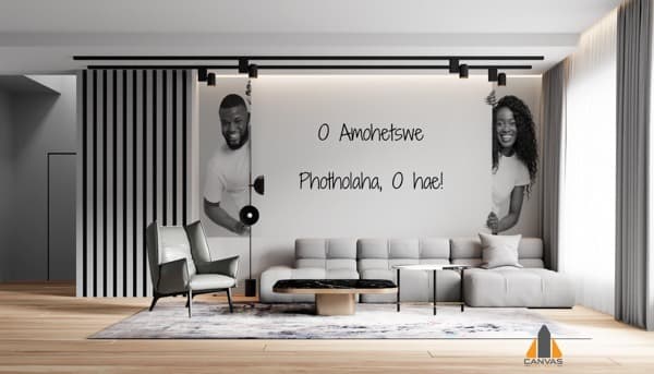 Smiling Black man and woman peeking playfully from behind a custom wallpaper installation of Setswana text.
