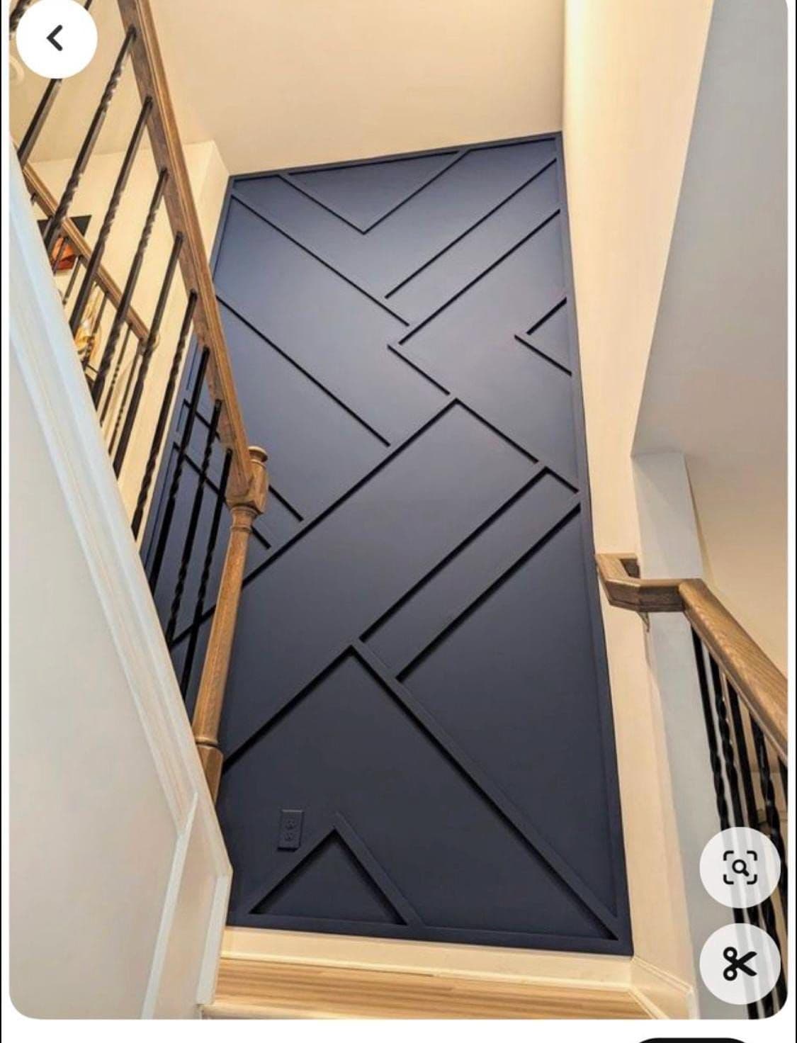 Navy blue geometric accent wall with wooden handrails, a unique wallpaper installation for narrow spaces.
