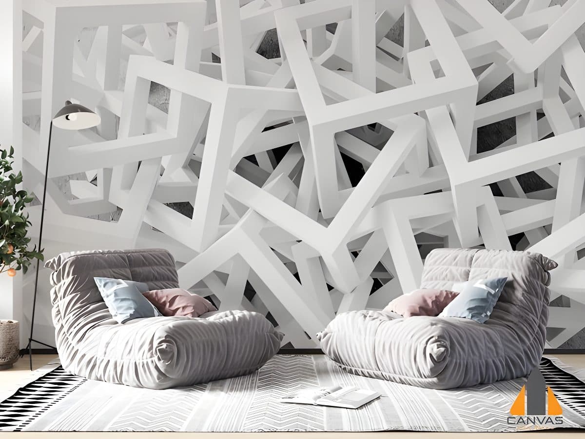 White modern geometrical wall mural in a cozy living room with soft gray chairs and a plant.