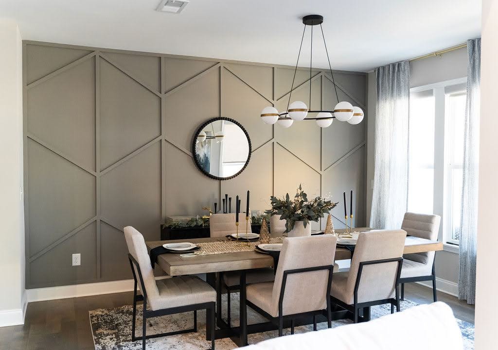 Dining room with gray geometric accent wall paneling, a circular mirror, and modern chandelier.
