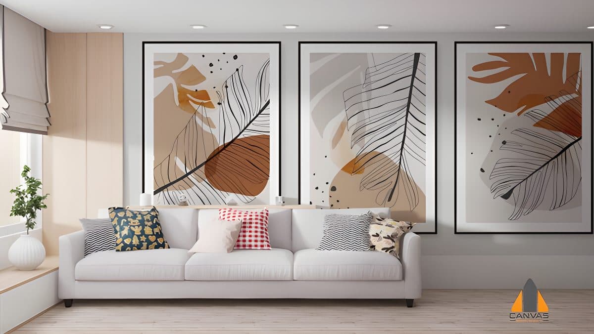 Three framed abstract botanical canvas prints above a white sofa in a modern living room.