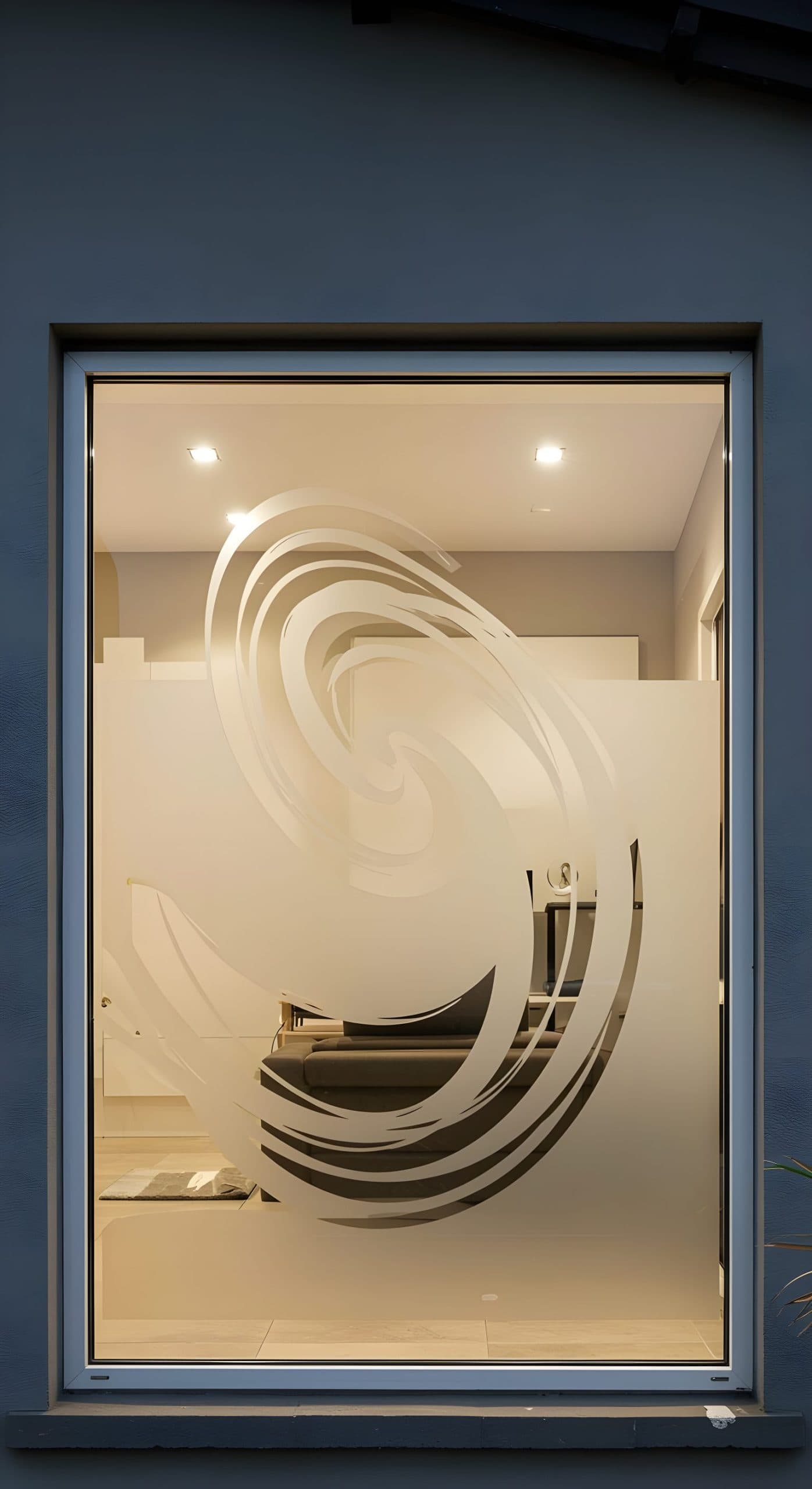 A window with a spiral swirl frosted film design, providing privacy for the indoor space.