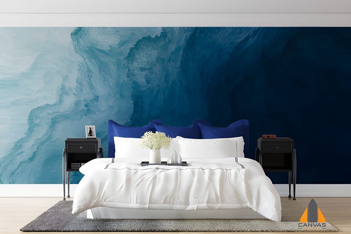 Bedroom with a blue abstract wave wall mural behind the bed, showcasing a custom wallpaper installation.