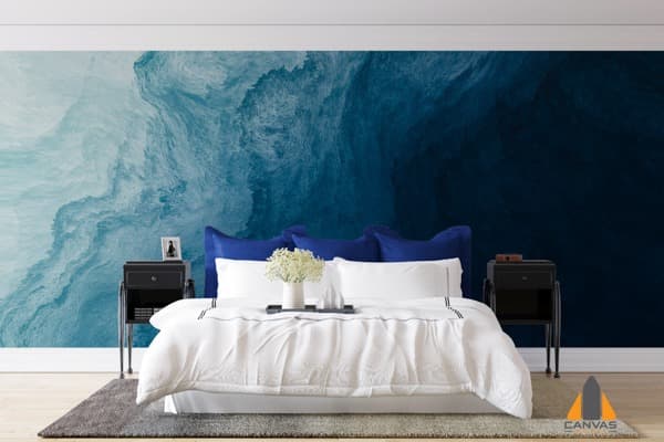 Bedroom with a blue abstract wave wall mural behind the bed, showcasing a custom wallpaper installation.