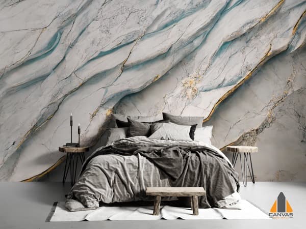 A bedroom with a bed and concrete floor, featuring a dramatic marble-effect wall mural with gold and blue veins.