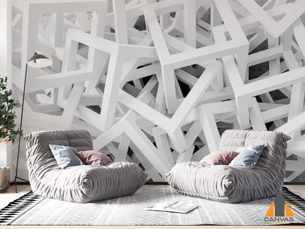 White modern geometrical wall mural in a cozy living room with soft gray chairs and a plant.