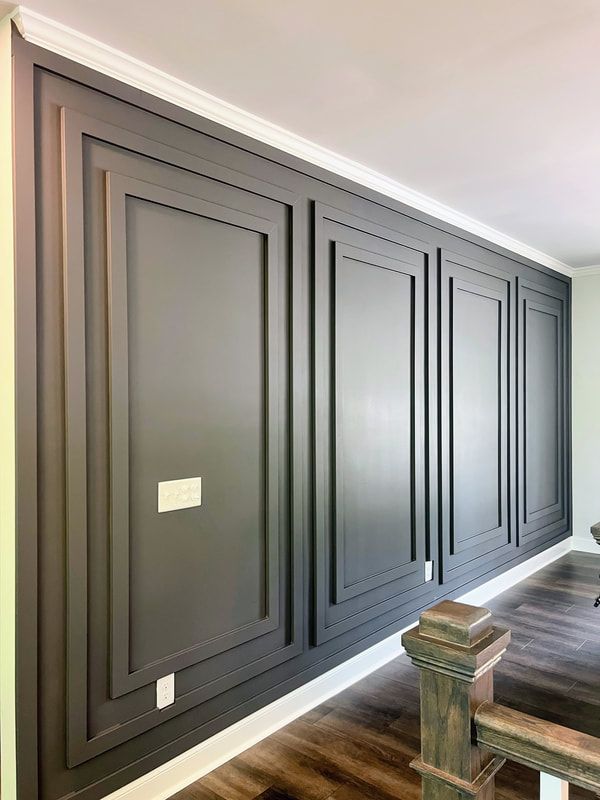Dark gray accent wall with raised panels in a modern home, perfect for custom wallpaper installations.